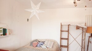 Ein Schlafzimmer mit einem Bett, einer Sterndeko, einem Bücherregal und einer Leiter.
