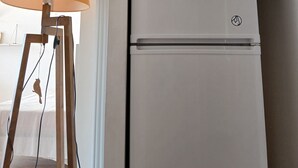Ein weißer Kühlschrank mit Logo, eine Lampe mit beiger Schirm und Holzboden.
