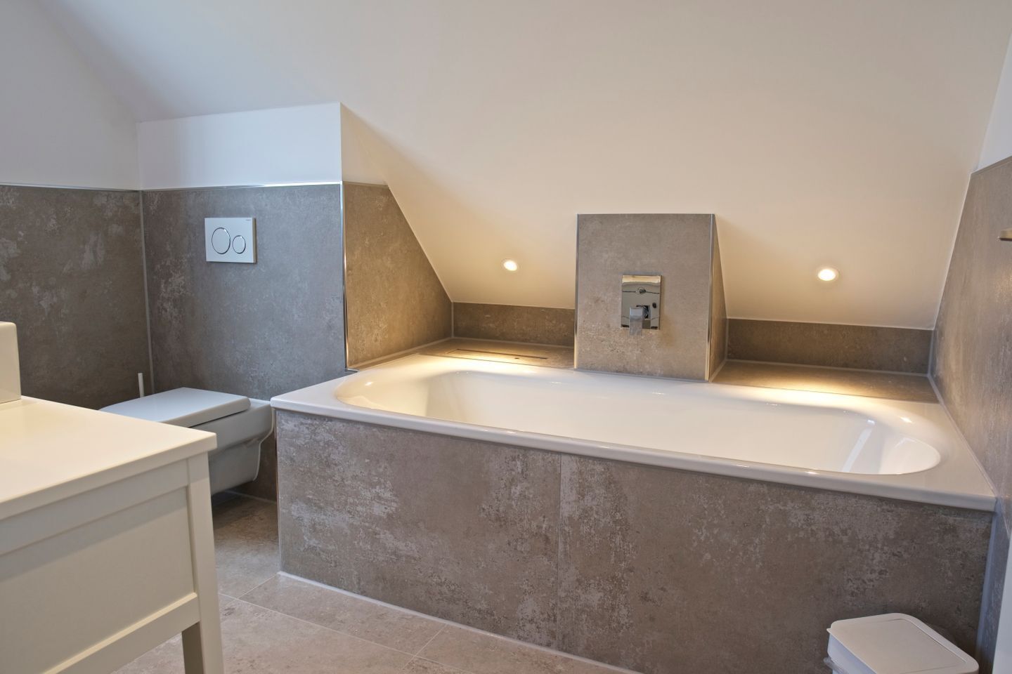 Un baño moderno con una bañera independiente, un inodoro y un tocador.