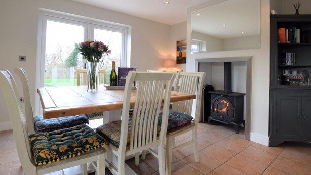 A dining area with a table and chairs, a fireplace, and a bookshelf. - 3 Bed in York (oc-hh015) (Tockwith)