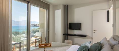 Une chambre d’hôtel avec un grand lit, une télévision, un balcon avec vue et un plateau de petit-déjeuner posé sur le lit.