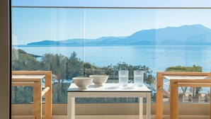 Een balkon met een tafel, twee stoelen en uitzicht op een wateroppervlak en bergen.