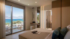 Een moderne slaapkamer met een groot bed, uitzicht op zee en een balkon met buitenmeubilair.