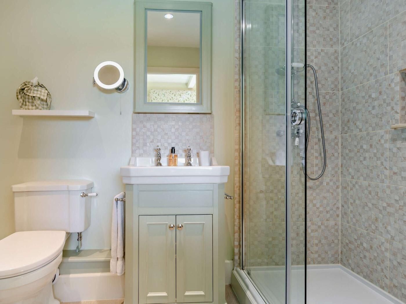 Une salle de bain comprenant des toilettes, un lavabo avec un miroir, une douche et un porte-serviettes.