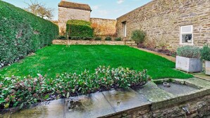 Un edificio de piedra con un césped verde y un pequeño jardín.