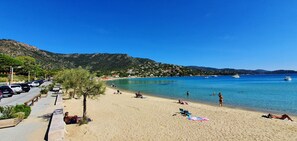 Una playa con cielo azul despejado, orilla arenosa y algunas personas relajándose.