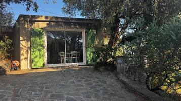 A building with a stone-paved entrance, a green door, and a table with chairs outside.