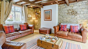 Ein gemütliches Wohnzimmer mit Ledersofas, einem Holztisch und einer Steinwand.