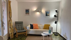 A living room with a sofa, armchair, small table, and floor lamp. - Domaine Anoutous, Carry – Peaceful Vacation Home Close to the Beach (Le Lavandou)