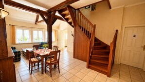 A dining area with a wooden table and chairs, a staircase, and a view of the outdoors. - Charming Vacation Rental in a Half-Timbered House (Egestorf)