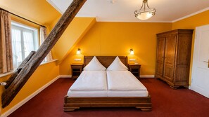 Een slaapkamer met een houten bed, twee nachtkastjes met lampen, een kledingkast en een schuine plafond.
