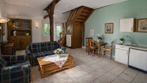 A cozy living room with a sofa, a coffee table, and a staircase leading to a kitchen area. - Charming Vacation Rental in a Half-Timbered House (Egestorf)