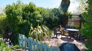 Ein Terrassenbereich mit weißem Zaun, einem Tisch und Stühlen.