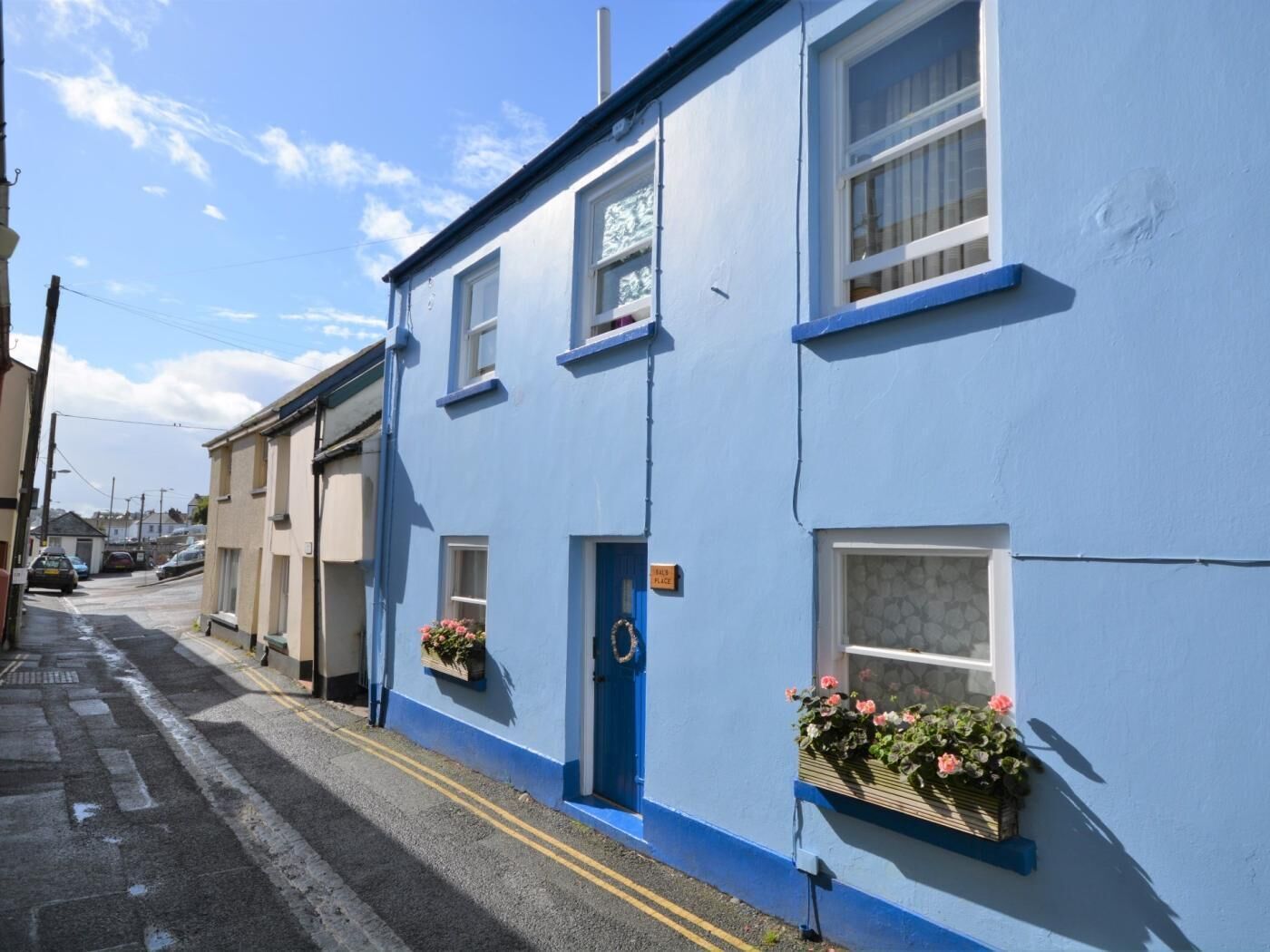 A blue building with a blue door, windows, and flower boxes on the windowsills.
