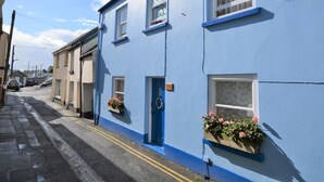 Ein blaues Gebäude mit blauer Tür, Fenstern und Blumenkästen an den Fensterbänken.