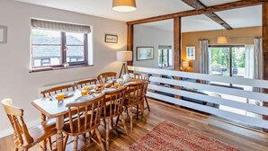 Uma área de refeições com uma mesa e cadeiras de madeira, uma luminária e vista para o exterior.