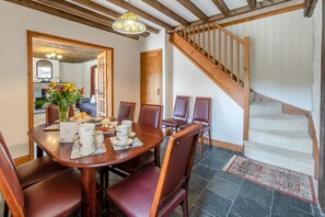 A dining area with a wooden table set for four, surrounded by chairs, and a staircase leading to an upper level. - 3 Bed in Bodmin (oc-ltbra) (Cardinham)