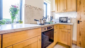 Eine moderne Küche mit Holzausstattung, einem Backofen und einer Mikrowelle.