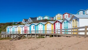 A row of colorful beach huts with a wooden fence in the foreground. - 3 Bed in Bideford (oc-glake) (Hartland)