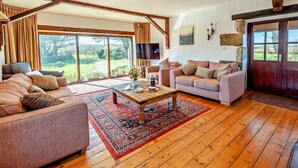 A spacious living room with a large window, a wooden coffee table, and two sofas. - 5 Bed in Redruth (oc-hellf) (Illogan)
