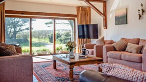 A spacious living room with a large window, a flat-screen TV, and a cozy seating area. - 5 Bed in Redruth (oc-hellf) (Illogan)