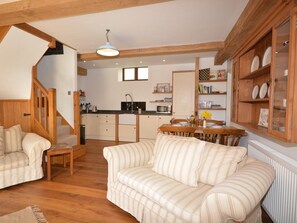 A cozy living room with a striped sofa, a wooden dining table, and a kitchen in the background. - 2 Bed in Blagdon (oc-tforg) (Nempnett Thrubwell)