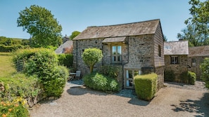 A stone building with a gravel driveway, a small patio with a table and chairs, and a well-maintained garden. - 1 Bed in Tavistock (oc-highm) (Cudlipptown)