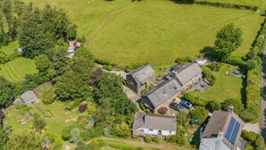 An aerial view of a rural property with multiple buildings, green fields, and scattered trees. - 1 Bed in Tavistock (oc-highm) (Cudlipptown)