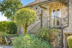 A stone building with a staircase leading to a balcony, surrounded by greenery. - 1 Bed in Tavistock (oc-highm) (Cudlipptown)