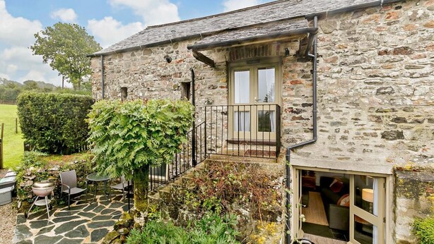 A stone building with a balcony, a patio with outdoor seating, and a garden area. - 1 Bed in Tavistock (oc-highm) (Cudlipptown)