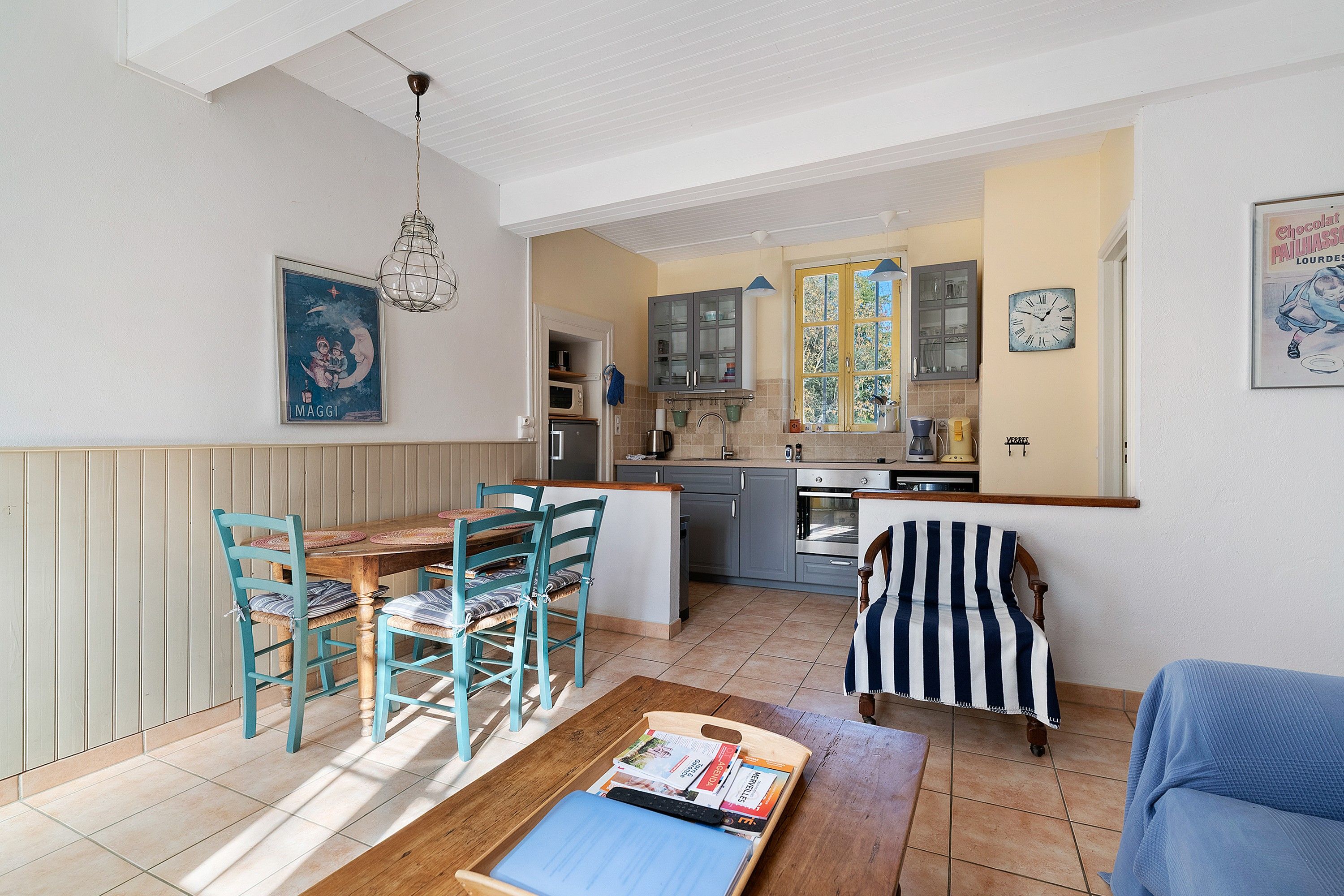 A spacious living area with a dining table, chairs, and a reading area with a bench and magazines.