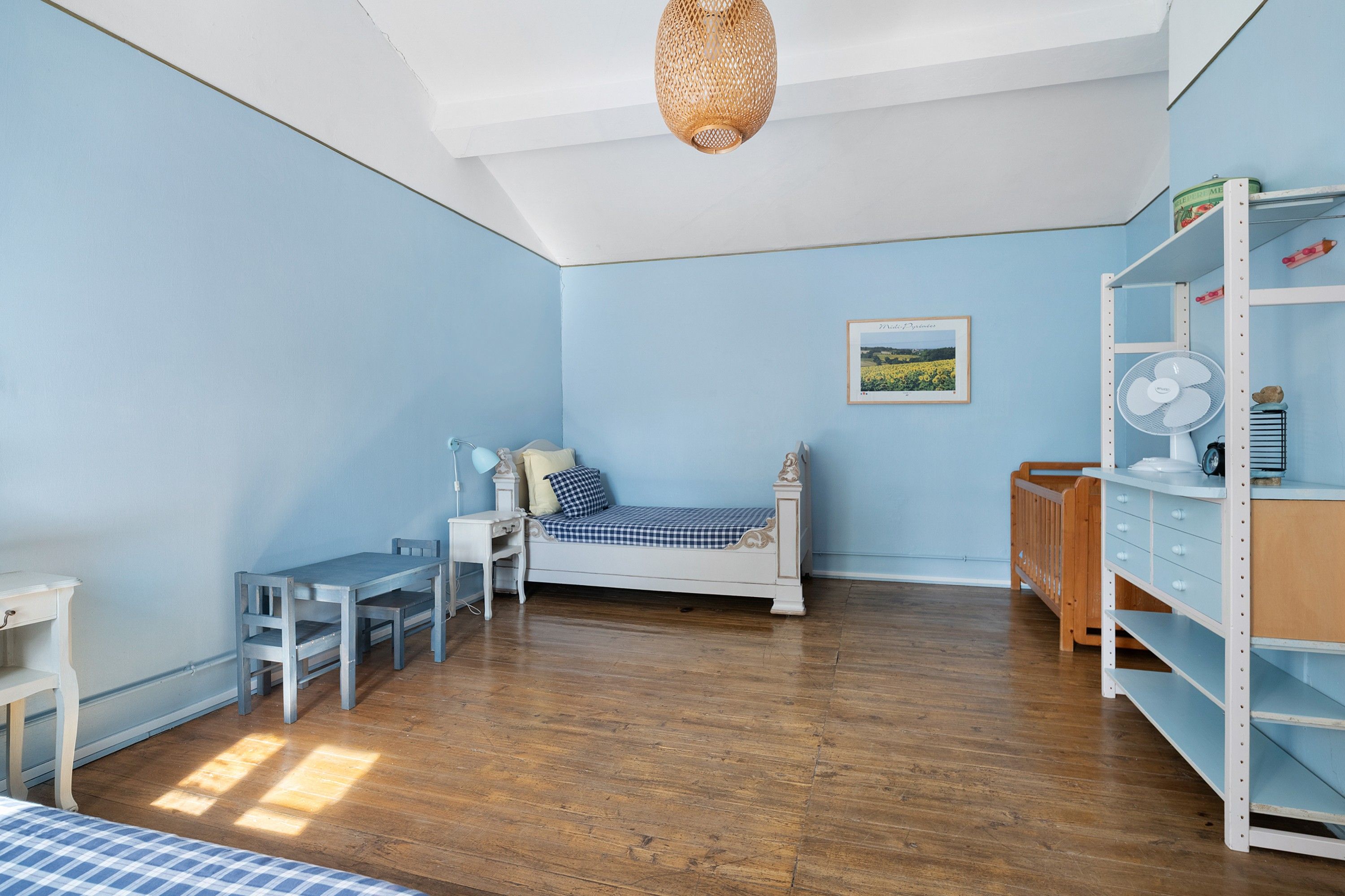 A room with a bed, a desk, a chair, a shelf, and a hanging light fixture.