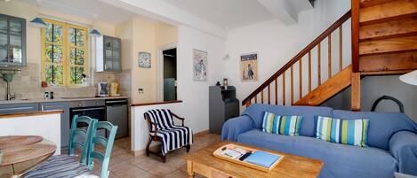 A cozy living room with a blue sofa, striped armchair, and wooden coffee table.