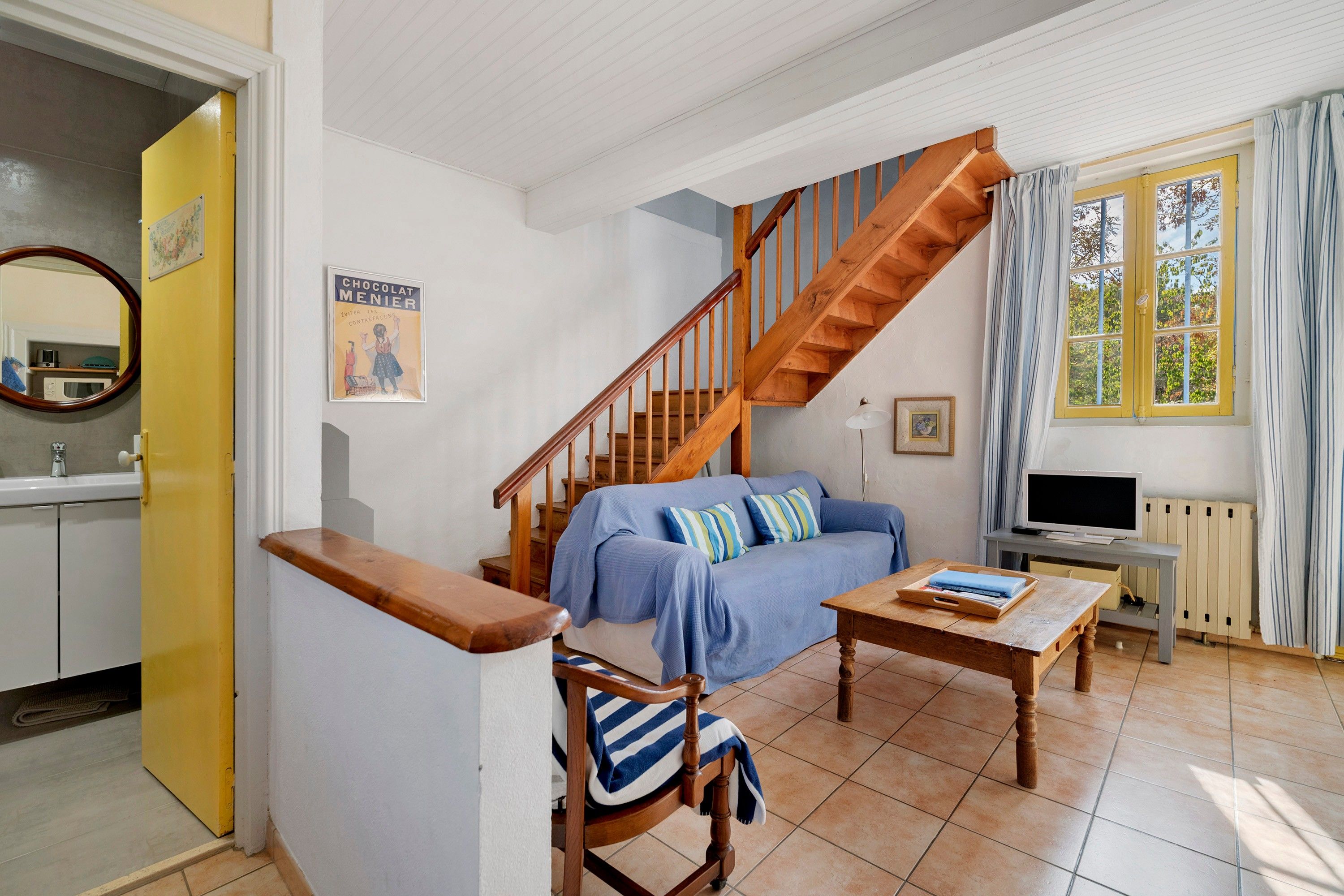 A living room with a wooden staircase, a sofa, a coffee table, and a television.