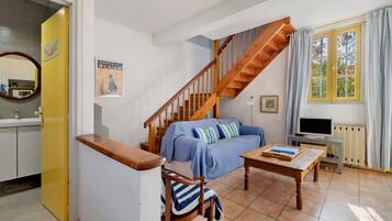 A living room with a wooden staircase, a sofa, a coffee table, and a television.