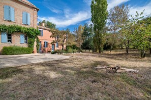 A rustic house with a brick facade, a gravel driveway, and a well-maintained lawn.