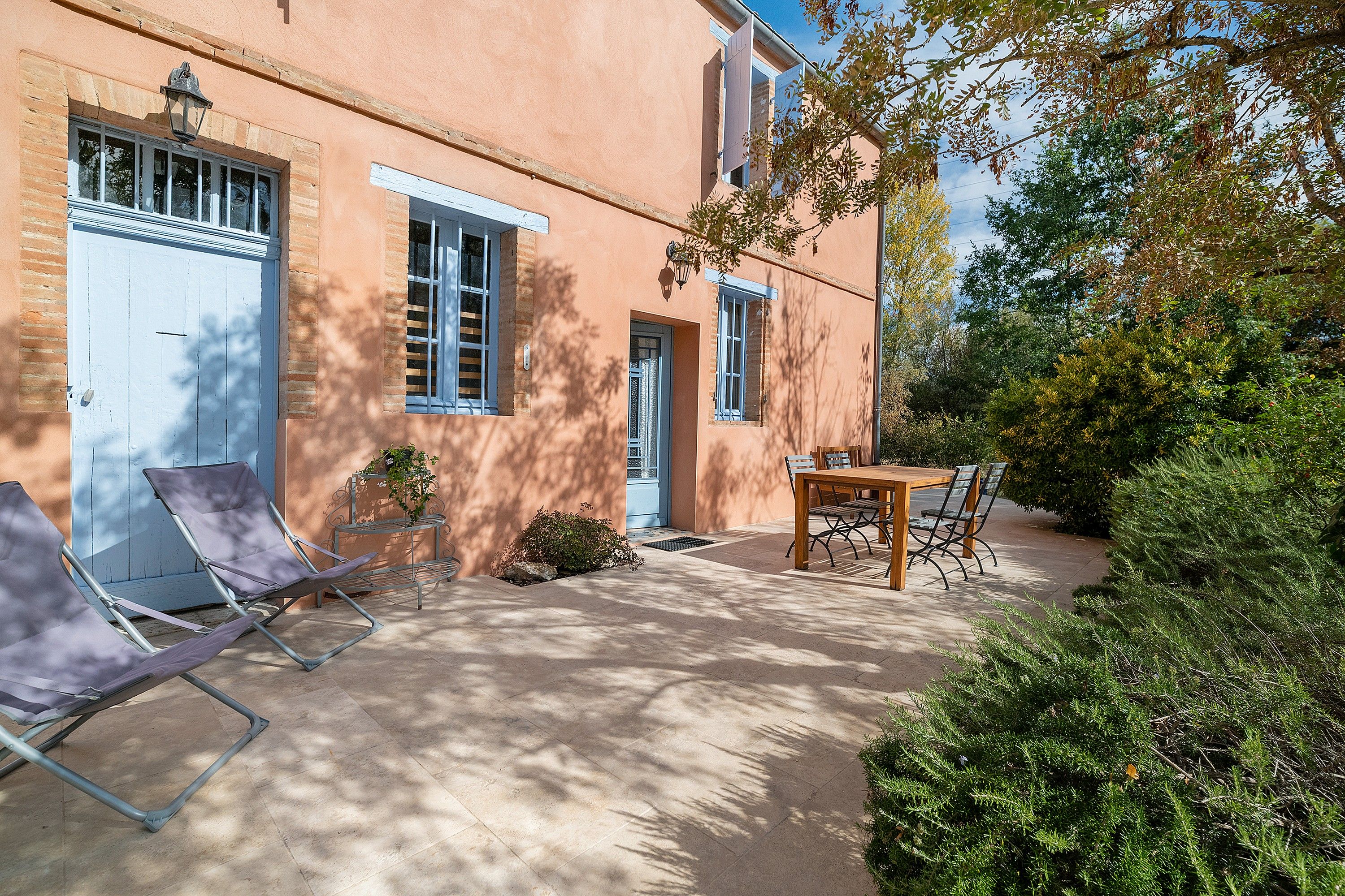 A building with a door, windows, and a patio area with a table and chairs.