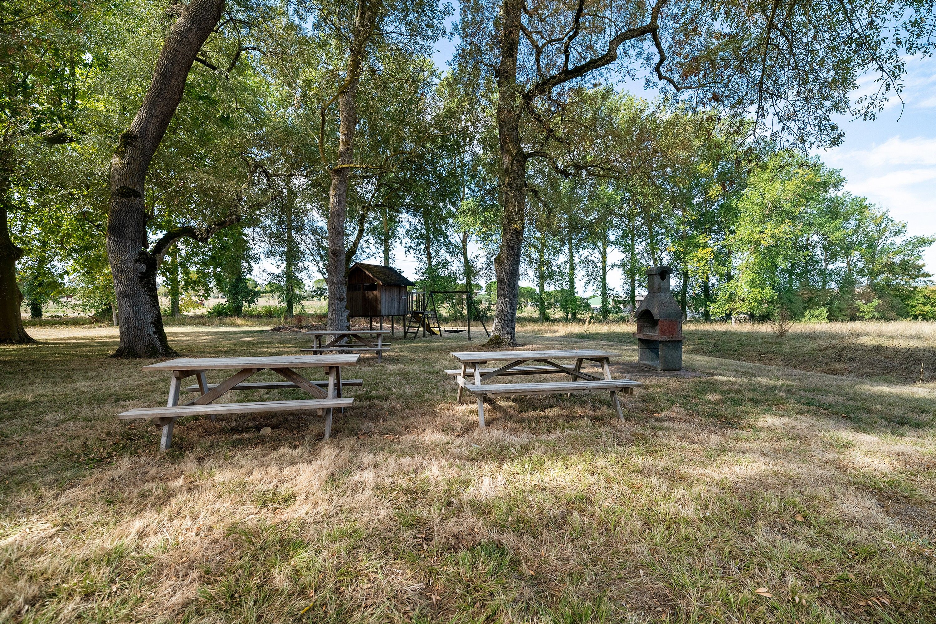 Un espace pique-nique équipé de bancs en bois et d’un barbecue en pierre.