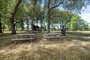 Un espace pique-nique équipé de bancs en bois et d’un barbecue en pierre.