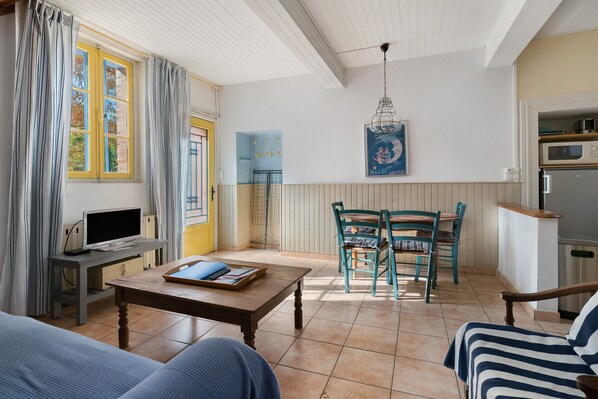 A cozy living room with a television, a dining table, and chairs.