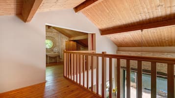 Interior de madera con techo alto y vista al exterior por una ventana.