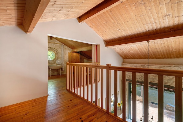 Un intérieur en bois, avec un plafond haut et une vue sur l’extérieur par une fenêtre.