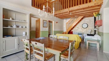 A spacious dining area with a wooden table and chairs, a kitchen with white cabinets, and a staircase leading to an upper level.
