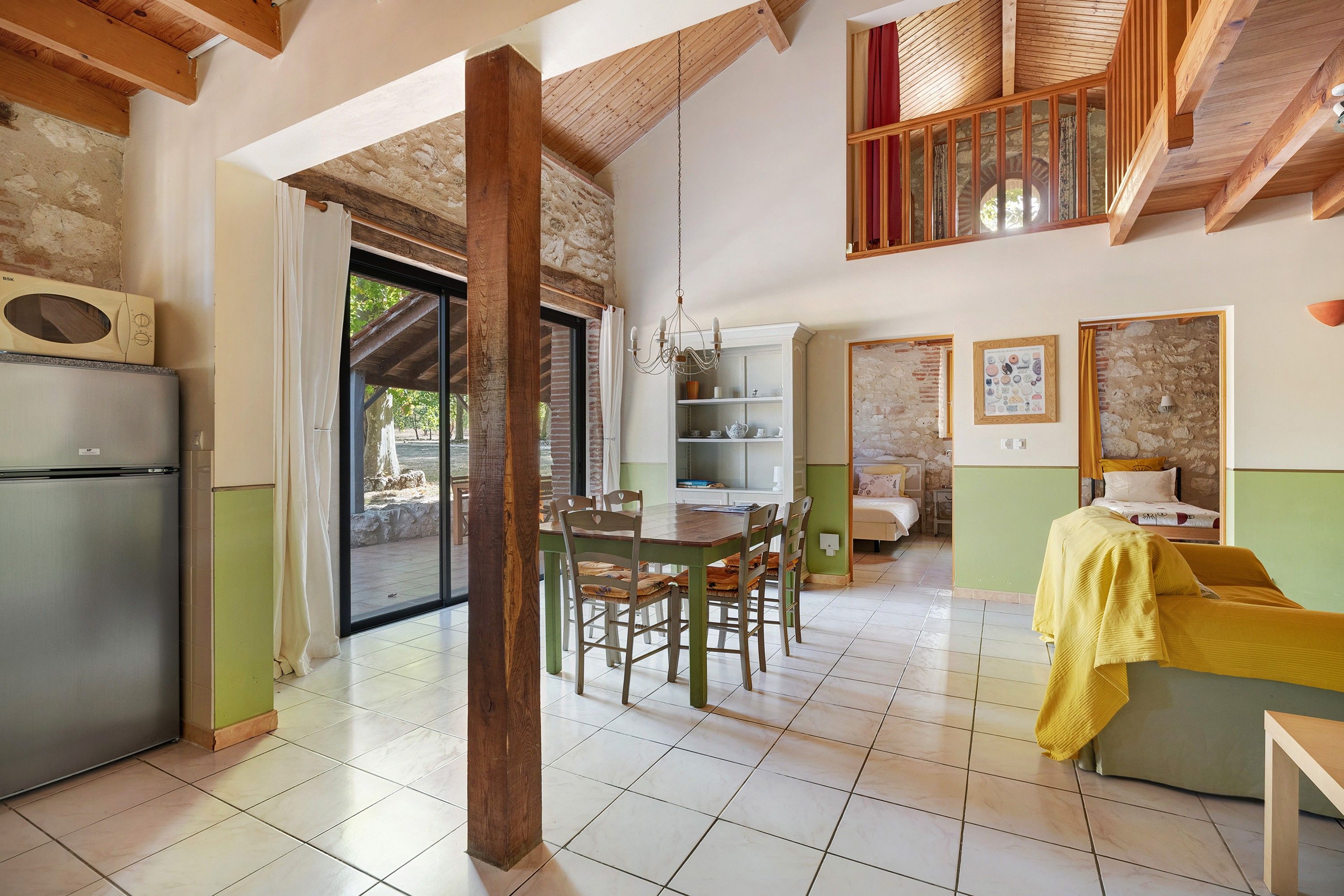 Amplia sala de estar con mesa de comedor, sillas, sofá y una zona de cocina con refrigerador.
