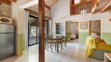 Amplia sala de estar con mesa de comedor, sillas, sofá y una zona de cocina con refrigerador.