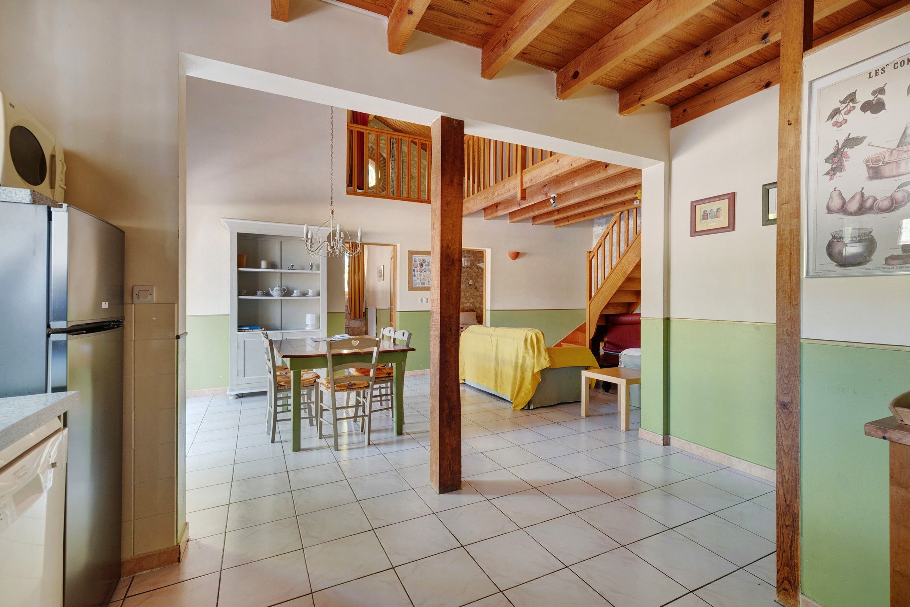 A spacious kitchen with a dining area, a staircase, and a living room with a sofa and a table.
