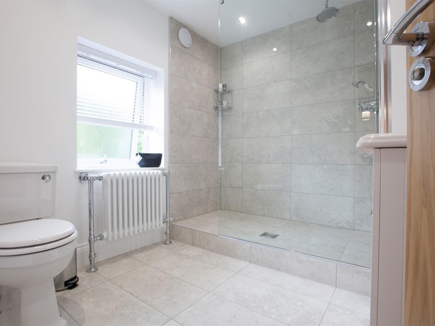 Et badeværelse med toilet, et vindue, en bruser og en radiator.