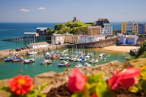 A coastal town with a marina filled with boats, historic buildings, and a prominent statue on a hill. - 2 Bed in Tenby (oc-fb186) (Tenby)