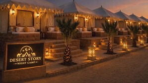 A row of tents with outdoor seating and a sign for 'Desert Story Night Camp.' - Desert Dhora Luxury Resort Jaisalmer (Jaisalmer)