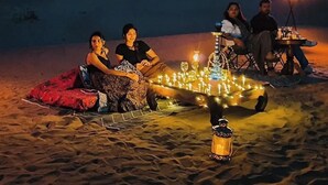 A group of people sitting on a sand dune at night with a campfire and lanterns. - Desert Dhora Luxury Resort Jaisalmer (Jaisalmer)